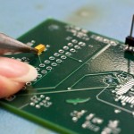 Tammy Koehler points out an electrical component on one of the circuit boards she is assembling. The components come in a variety of shapes and sizes.