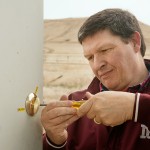 Tribal Chairman Gerald Gray attaches a new lock to the rear door of the Little Shell Chippewa Tribe Cultural Center during a visit to Great Falls. The cultural center is backdropped by Hill 57, a historical landmark to the tribe.