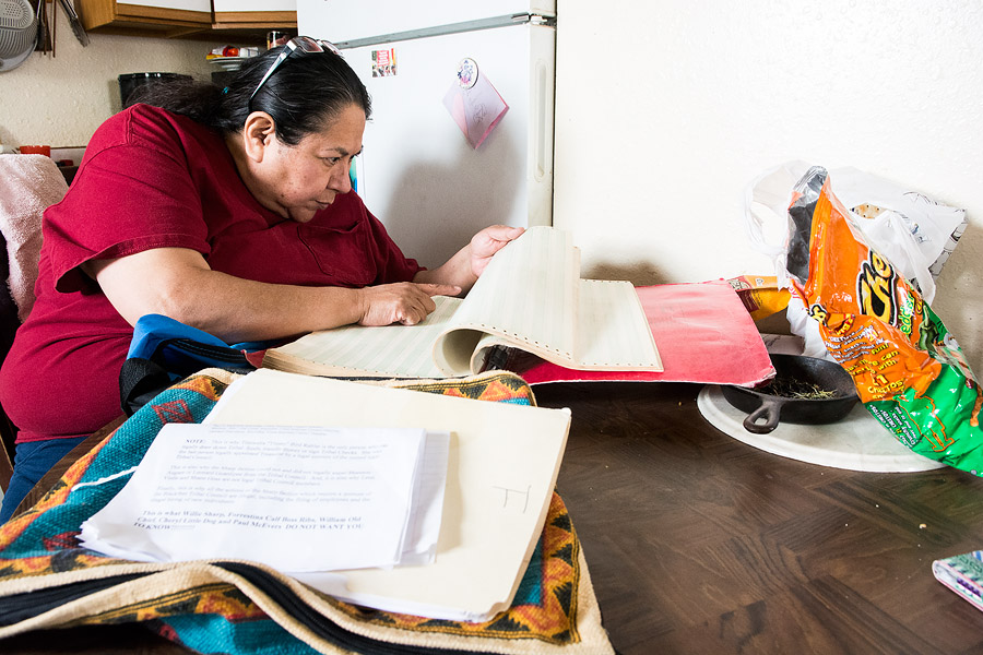 Anna Bull Shoe sits at her kitchen table in Browning, reading from a thick document naming enrolled members of the Blackfeet tribe. Bull Shoe uses the document to verify signatures on her petition to remove the entire Blackfeet Tribal Business Council. To sign the petition, a tribal member must be 18 and eligible to vote.