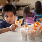 "I hate carrots,” says 6-year-old Max Littlebird as he reaches for a healthy snack at the Boys & Girls Club of the Northern Cheyenne Nation. The club's food is funded by a program that requires it to serve healthy foods to kids, such as carrots with ranch dressing.