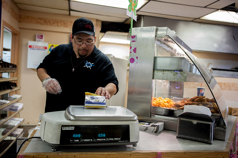 Mac Cooper, an employee of the Cheyenne Depot, weighs chicken strips for a customer. The Depot is the only gas station and the larger of two convenience stores on the Northern Cheyenne Indian Reservation. Fried foods are popular on the reservation.