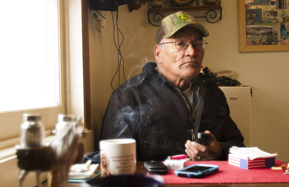 Ivan Wing takes a coffee and cigarette break while helping a neighbor move some equipment. There are big distances between the three communities on the reservation, making neighborhood ties strong.