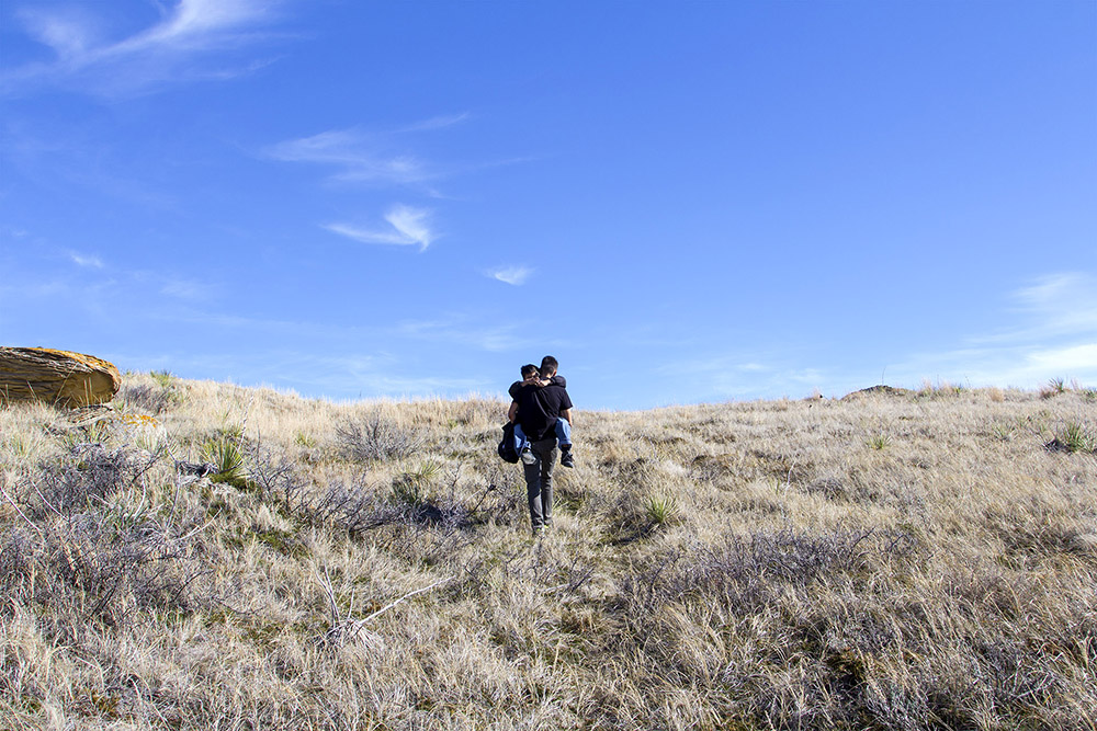 Francis Bauer carries his son, Killian, back to the truck after spending an afternoon exploring the badlands just south of Poplar, Montana. Francis, a student at the University of Montana, returned home to the Fort Peck reservation for spring break to visit his son.