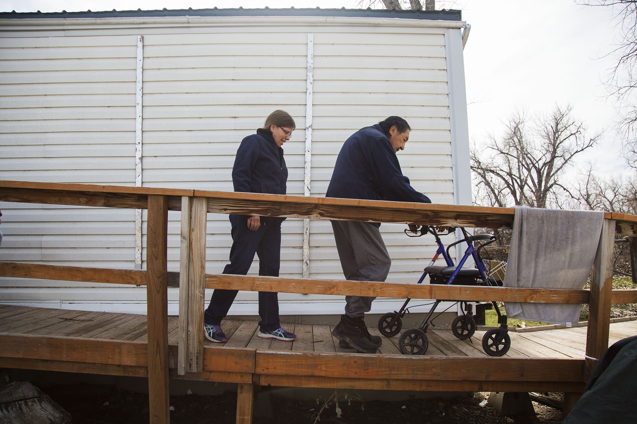 Patti Medicinehorse, left, and Thomas Larson Medicinehorse, right, make their way down the ramp in front of their home in Crow Agency. Their home is a FEMA trailer that they received after their old home was submerged in water after the Little Big Horn River flooded Crow Agency in May 2011.